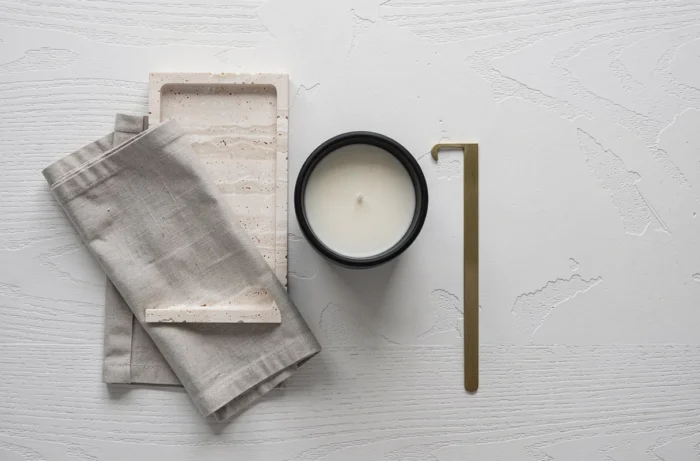 Flat lay de accessoires décoratifs tendance pour la maison avec plateau en travertin, bougie et lin sur surface en chêne blanc