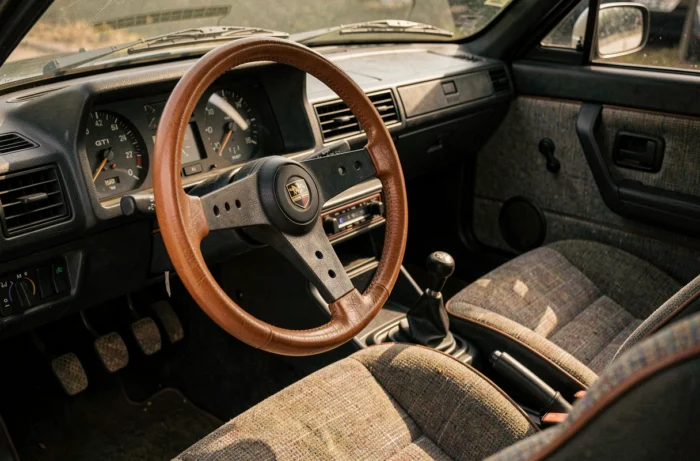 Intérieur de la Peugeot 305 GTI avec volant sport, tableau de bord analogique et siège baquet d'époque